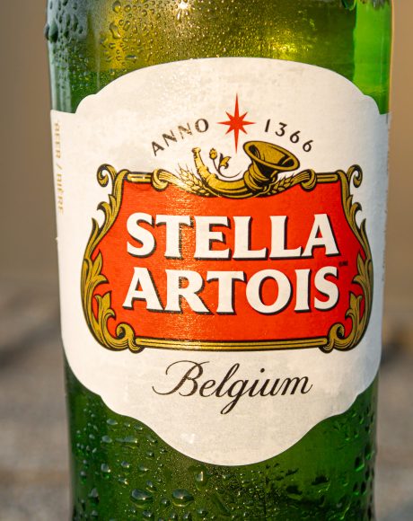 Stella beer with water drops running down, with a warm light.