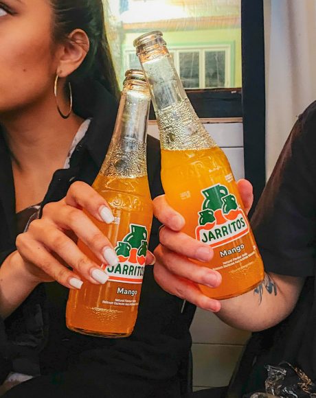 two orange flavoured Jarritos soda cheering