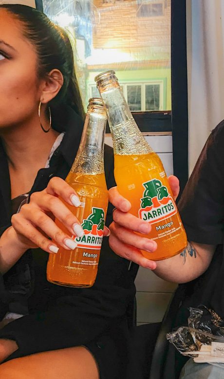 two orange flavoured Jarritos soda cheering