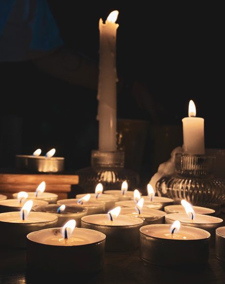 several candles turned on and grouped together in a dark room.